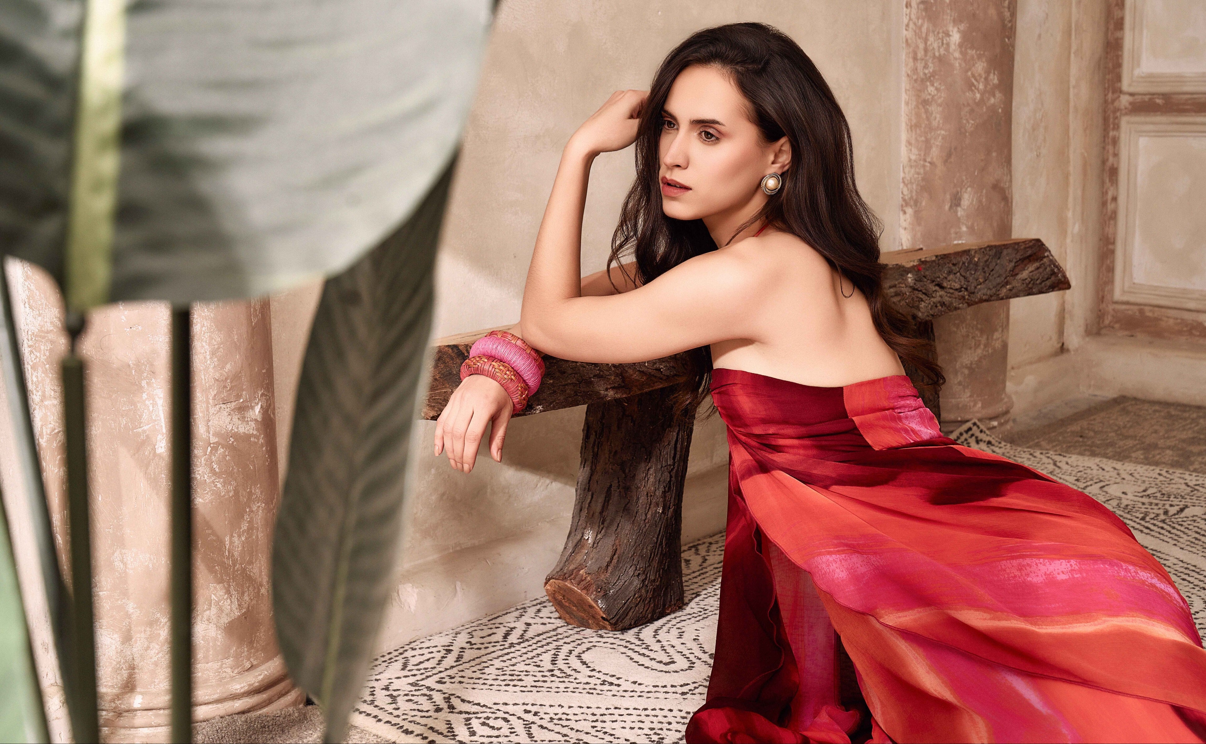 Woman in a red dress sitting on a stone bench in an outdoor setting
